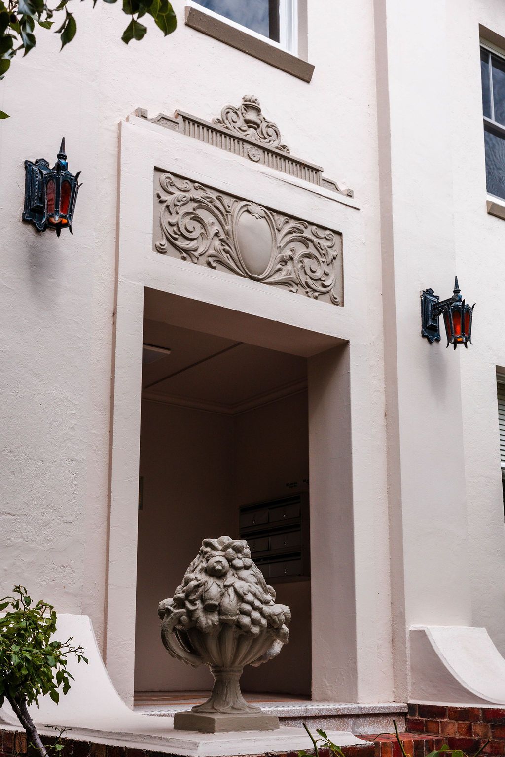 Close-up of the entrance to the Toorak showroom, adorned by vintage dark red lamps on both sides
